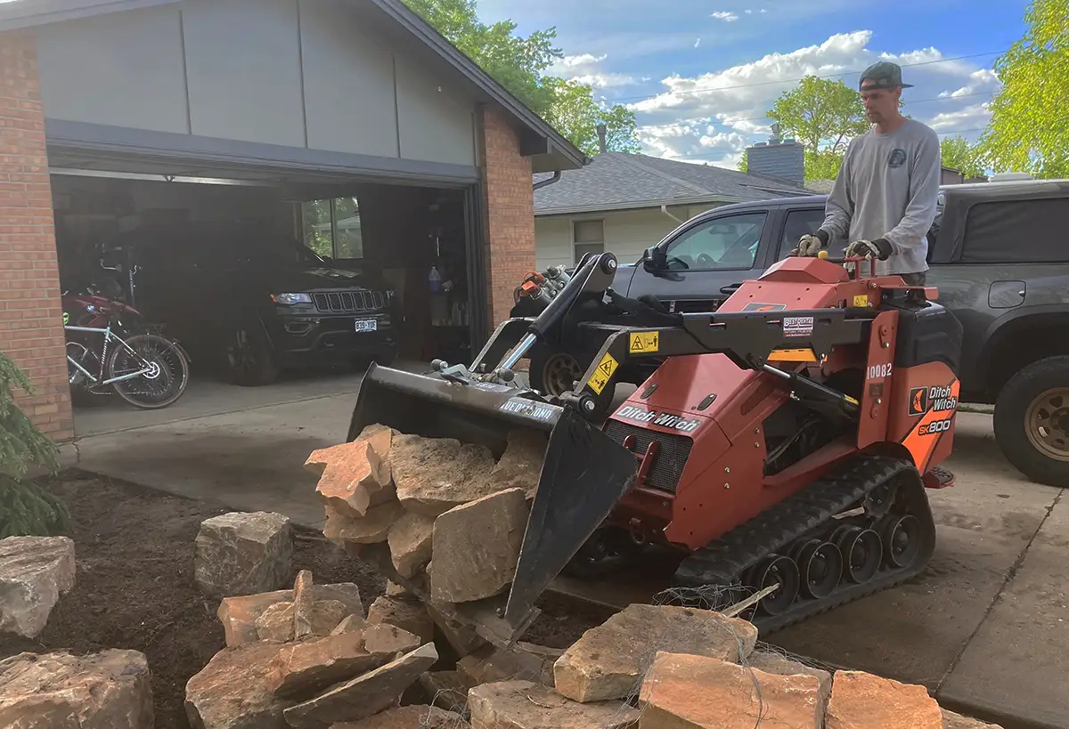 Stuart Shoemaker operating heavy machinery at Blue Spruce Horticulture in a front yard.